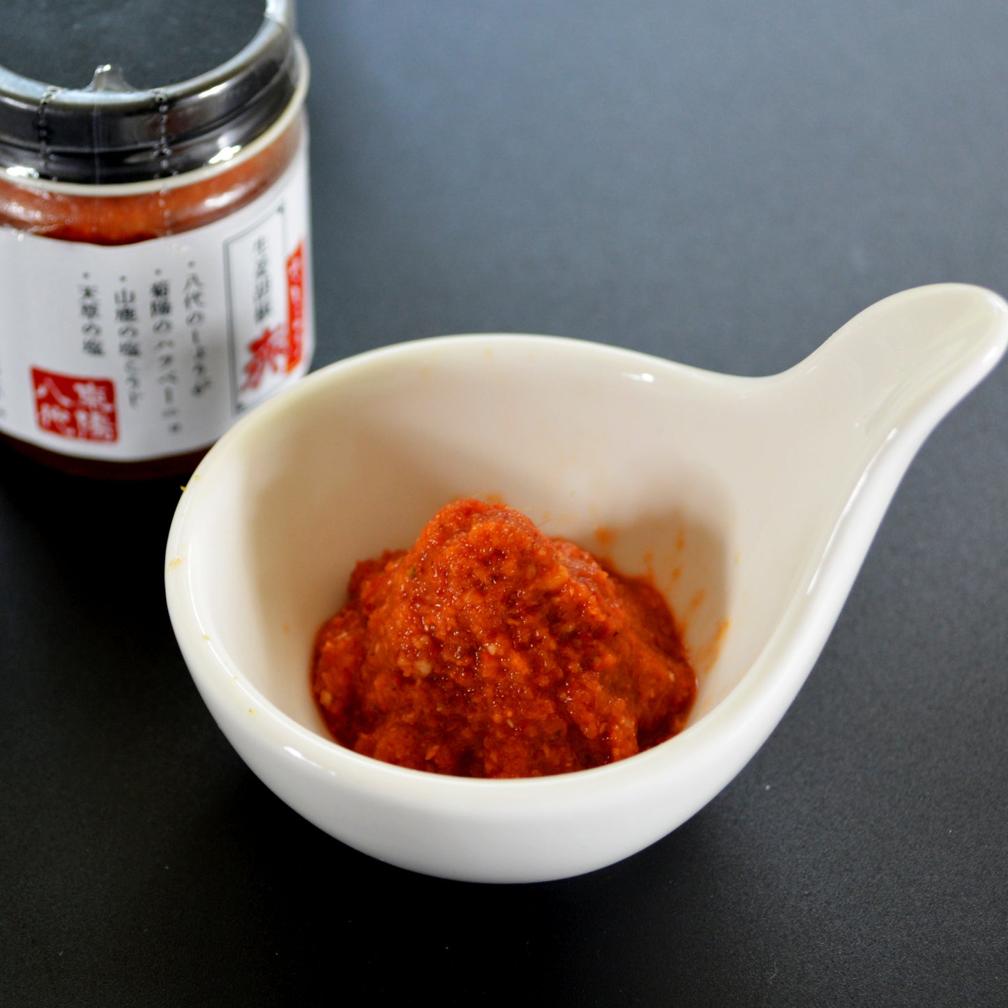 斜め上から撮影された、薬味皿に盛り付けられた生姜胡椒と瓶